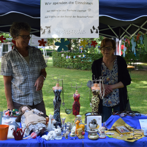 Karla Seehausen (links) und ein Mitglied des Heimbeirates auf dem Sommerfest 2023 mit dem Flohmarktstand.