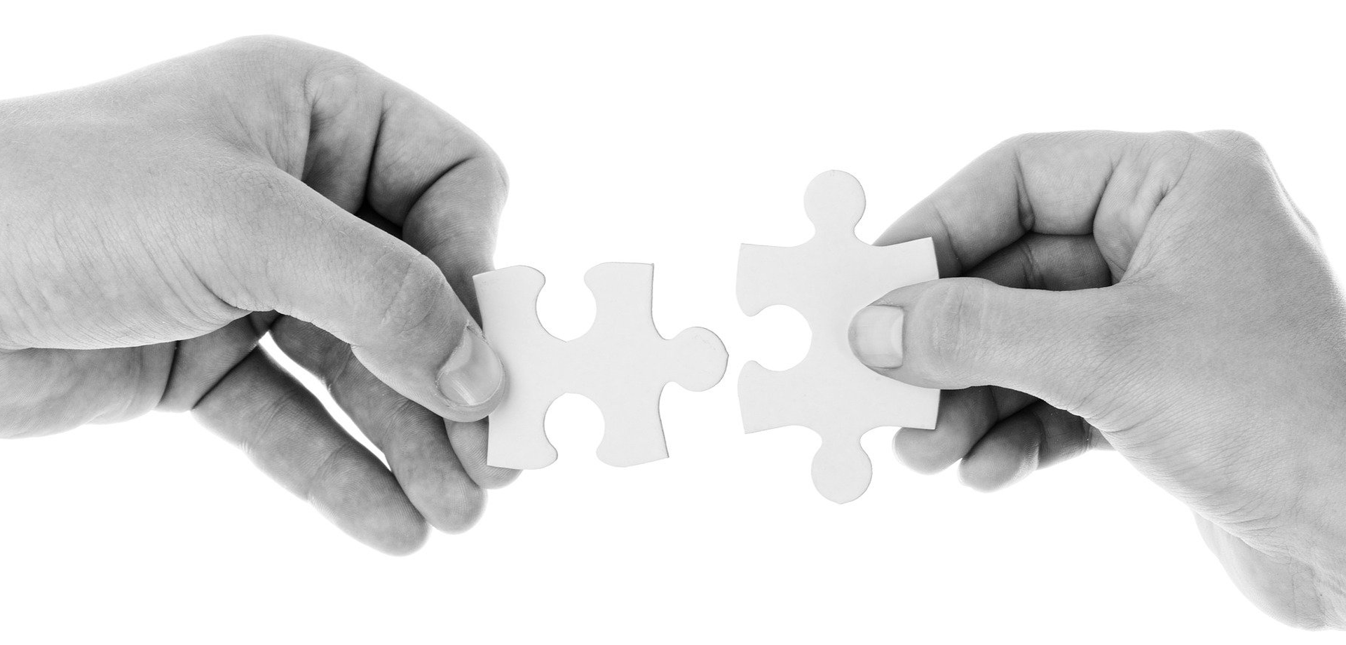 Zwei Hände halten jeweils ein Puzzle-Teil und führen sie zusammen.